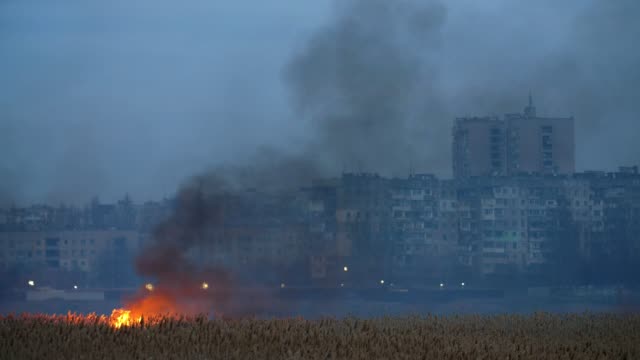 Astonishing-view-of-the-burning-cane,-sedge,-and-reed-on-the-Dnipro-riverbank-in-the-outskirts-.-The-houses-are-faraway.