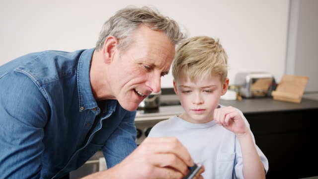 Grandson-With-Grandfather-Assembling-Electronic-Components-To-Build-Robot-Together-At-Home