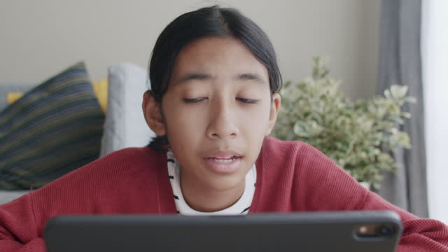 Asiatische-Studentinnen-lernen-online-über-Internet-Kommunikation-mit-Tutor-auf-Tablet-zu-Hause.-Nahaufnahme-des-Gesichtes-junger-Frau