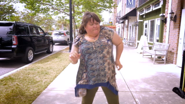 A-large-happy-woman-dancing-and-moving-her-arms-around-outside