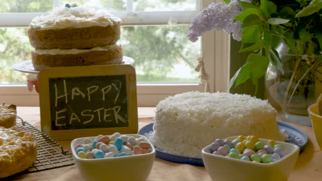 Hausgemachte-Desserts-und-ein-Zeichen,-das-frohe-Ostern-an-eine-kleine-Tafel-sagt