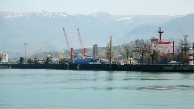 Port-city-with-spectacular-mountains-at-the-background,-commercial-transport