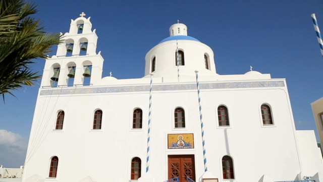 White-Christian-church-with-domes-and-bells-standing-against-blue-sky,-sequence