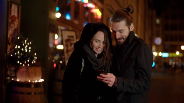 Young-happy-couple-using-smartphone-at-night.