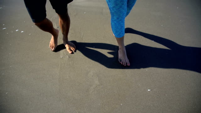 Multi-ethnic-couple-walking-holding-hands-on-beach