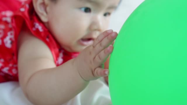 Cute-asian-little-baby-girl-having-fun-to-try-to-catch-and-play-with-balloon-in-slow-motion-shot