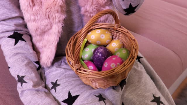 Niña-con-huevos-de-Pascua-en-cesta-y-zanahoria-en-sofá