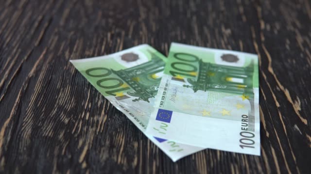 Billetes-en-euros.-Dinero-cayendo-en-el-fondo-de-madera