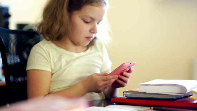 Die-Schülerin-schließt-das-Buch-und-fröhlich-nimmt-ihr-rosa-Handy.-Kommunikation-in-sozialen-Netzwerken.-Probleme-der-Bildung.-Internet-sucht
