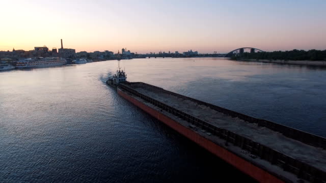 Barge-sails-along-the-river-near-the-city-port-on-sunset-aerial-footage