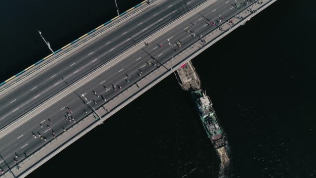 4K-Luftbild-Drohne-Fooage.-Marathonlauf-auf-der-Brücke.-Schiff-unter-Brücke