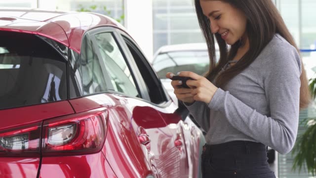 Aufnahme-einer-Frau-mit-ihrem-Smartphone-Stand-in-der-Nähe-ihres-Autos-beschnitten