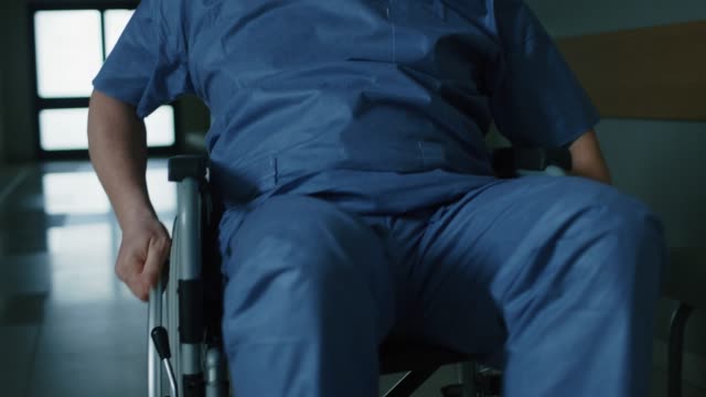 Im-Krankenhaus-Rückansicht-nach-Schuss-von-der-ältere-Mann-im-Rollstuhl-bewegen-durch-den-Flur.
