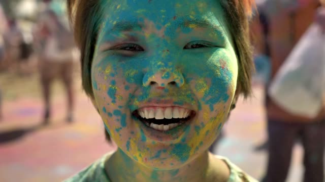 Gesicht-des-jungen-glücklich-Asiatin-ist-mit-bunten-Pulver-auf-Holi-Festival-tagsüber-im-Sommer,-Farbkonzept,-emotionales-Konzept-lächelnd.