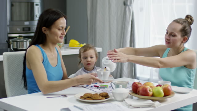 Mütter-mit-Kleinkind-Teetrinken-in-Küche
