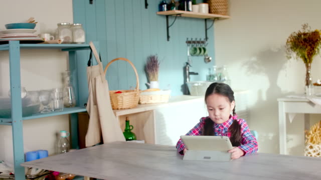 Niña-asiática-jugando-con-la-Tablet-en-casa
