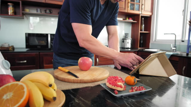 Man-Cutting-Apple-and-Using-Tablet
