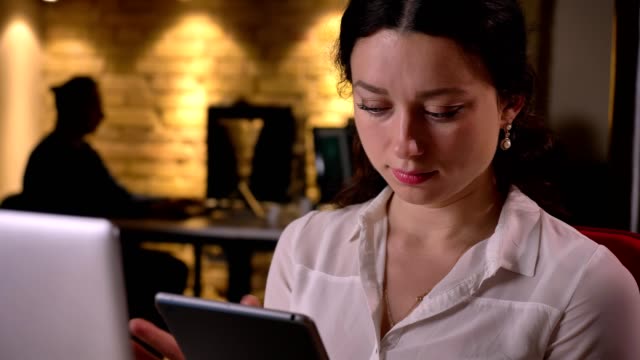 Closeup-of-young-caucasian-female-office-worker-scrolling-on-the-tablet-and-being-confused-indoors-on-the-workplace