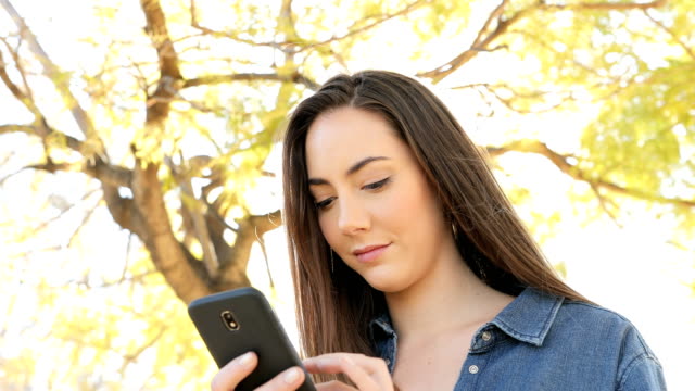Mujer-seria-usando-el-teléfono-inteligente-en-un-parque