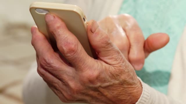 Hands-of-Senior-Woman-Using-Smartphone