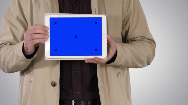 Männliche-Hände-halten-Tablet-mit-blauem-Bildschirm-Mockup-auf-Gradienten-Hintergrund