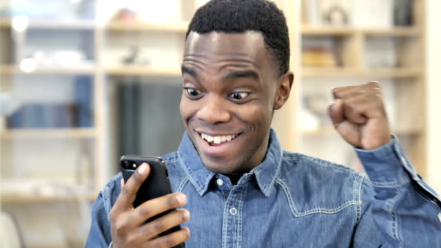 Aufgeregte-glückliche-afrikanische-Mann-mit-Smartphone