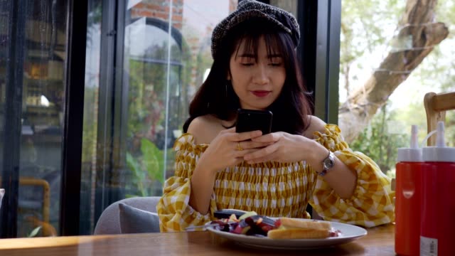 Asian-young-woman-taking-a-photo-of-breakfast-with-smartphone-social-media