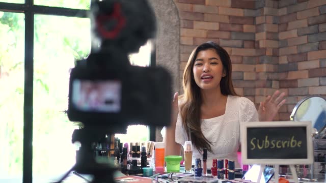 Mujer-asiática-grabando-video-sobre-cosméticos-con-DSLR-en-trípode