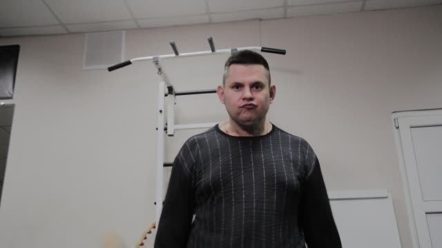 Cheerful-fat-man-performs-a-wrong-exercise-in-the-gym.-For-the-first-time-in-a-fitness-club
