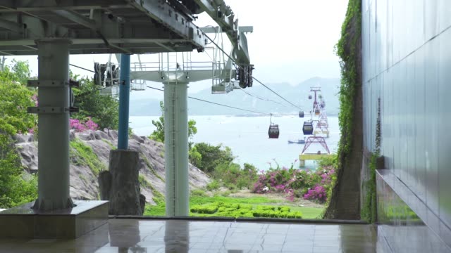 Cable-car-cabins-moving-on-rope-way-for-passenger-transportation-across-sea-in-modern-city.-Cable-way-with-car-cabins-between-island-in-sea