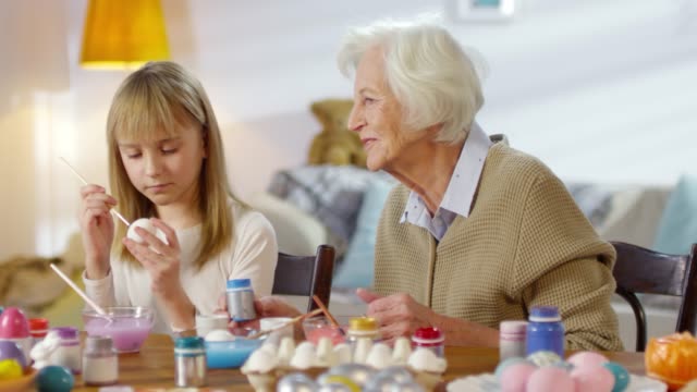 Grandmother-Watching-Granddaughter-Paint-Eggs