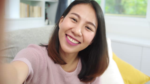 Junge-asiatische-Teenagerin-vlog-zu-Hause,-weiblich-mit-Smartphone-machen-vlog-Video-zu-sozialen-Medien-im-Wohnzimmer.-Lifestyle-Frau-entspannen-sich-am-Morgen-bei-zu-Hause-Konzept.