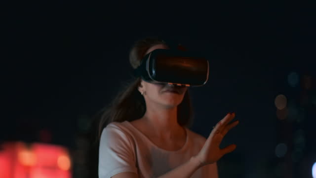 Jovencita-en-gafas-de-realidad-virtual-en-la-ciudad-nocturna-mueve-sus-manos