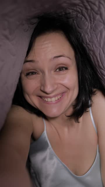 Frau-sitzt-auf-Bett-unter-Decke-Videochat-mit-Freund-auf-Smartphone-genießen