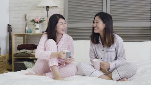 two-best-friends-talking-laughing-sitting-on-bed