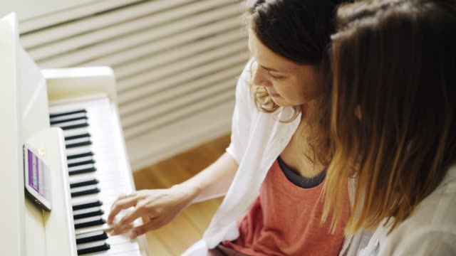 Freundinnen-lernen-Klavier-spielen-zu-Hause