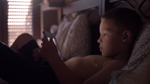 Kind-liegt-im-Bett-und-beobachtet-Cartoon-auf-Tablet-Computer