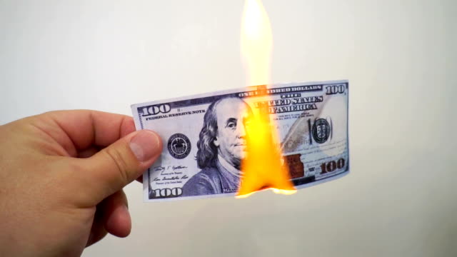Hand-hält-eine-brennende-hundert-Dollar-Banknote