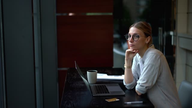 Mujer-pensativa-pensando-en-la-idea-mientras-trabaja-remotamente-en-netbook-digital-conectado-a-Internet-inalámbrico
