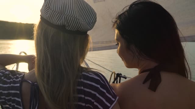 lesbische-paar-umarmt-auf-Segelboot-schwimmen-auf-Fluss-bei-Sonnenuntergang