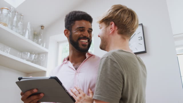 Männliche-Homosexuell-Paar-mit-digitalen-Tablet-zu-Hause-in-der-Küche-zusammen