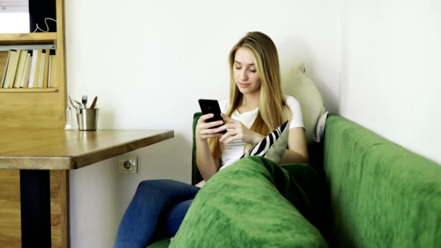 Attractive-young-happy-woman-using-mobile-phone-during-resting-in-a-cafe.-4K