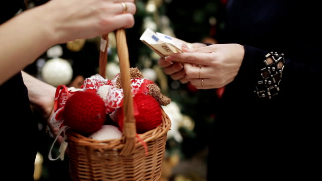 Comprar-adornos-navideños-en-la-tienda.-El-comprador-cuenta-y-da-el-dinero-al-vendedor-y-recibe-a-cambio-una-cesta-de-bolas-de-Navidad.