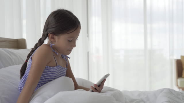 Asiatische-Mädchen-mit-Smartphone-im-Schlafzimmer