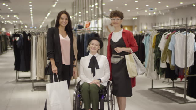 Frau-im-Rollstuhl-und-ihre-Freunde-posieren-im-Bekleidungsgeschäft