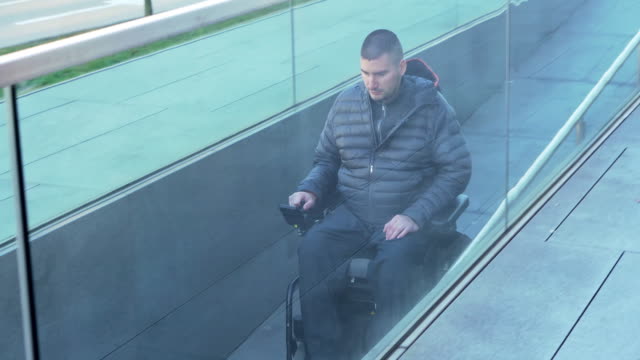 Man-on-electrical-wheelchair-using-a-ramp---Pan-follow-movement