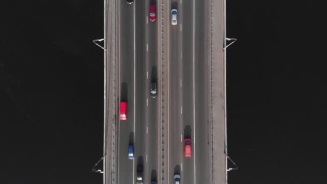 Bridge-highway-dark-water-colorful-cars-in-traffic-aerial-top-view