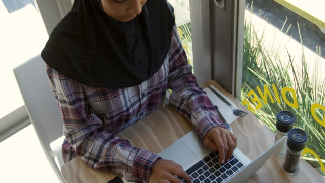 Mujer-joven-usando-computadora-portátil-en-un-café