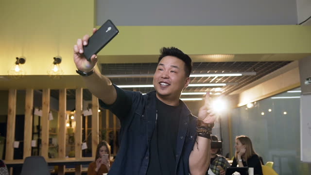 Hipster-männliche-Arbeiter-machen-Selfie-auf-dem-Smartphone-auf-modernen-Büro-Hintergrund