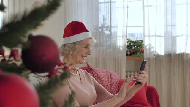 Elderly-woman-with-Santa-Claus-hat-on-head-enjoys-video-call